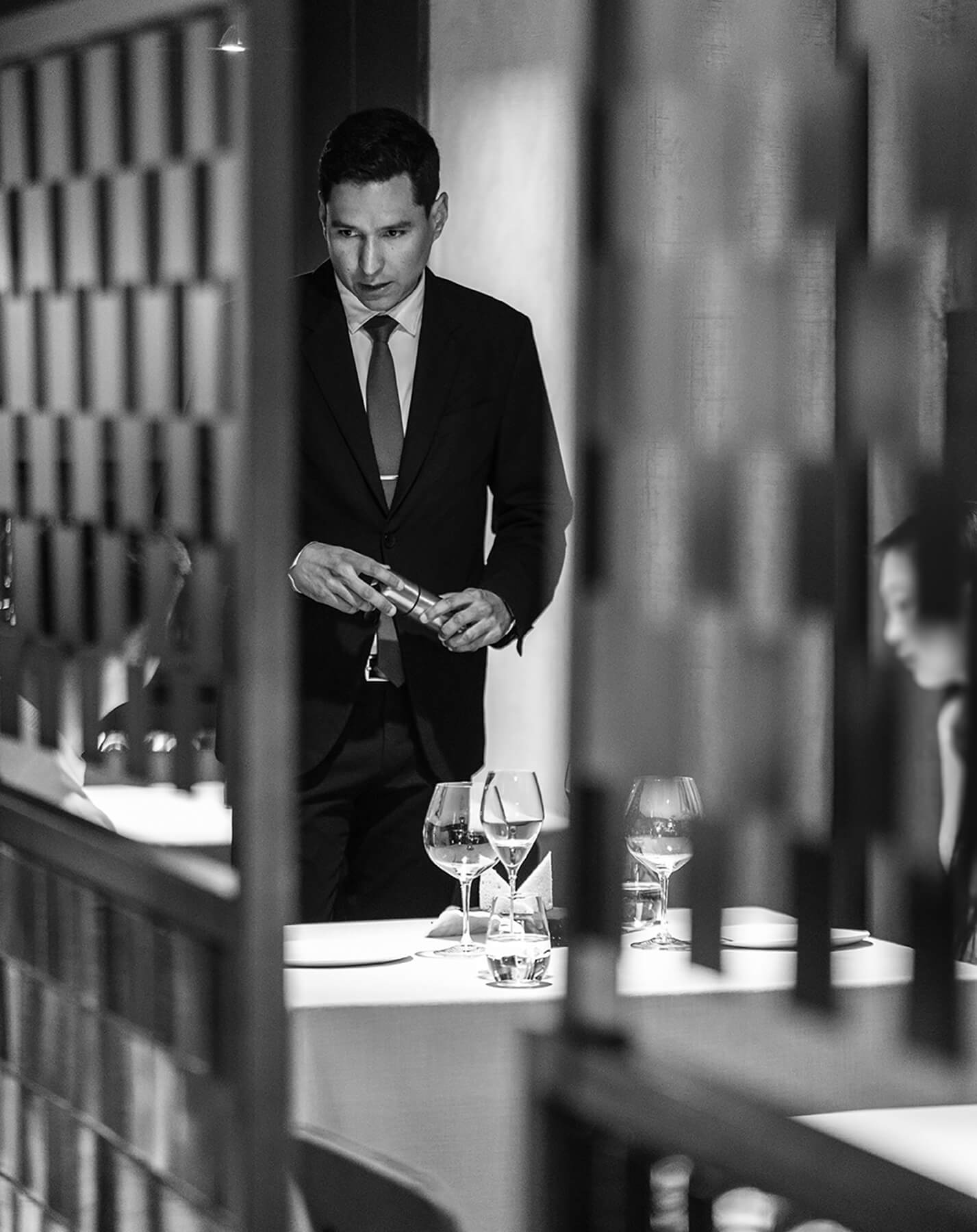 Camarero profesional atendiendo a una mesa en el restaurante Disfrutar en Barcelona, fotografía en blanco y negro.