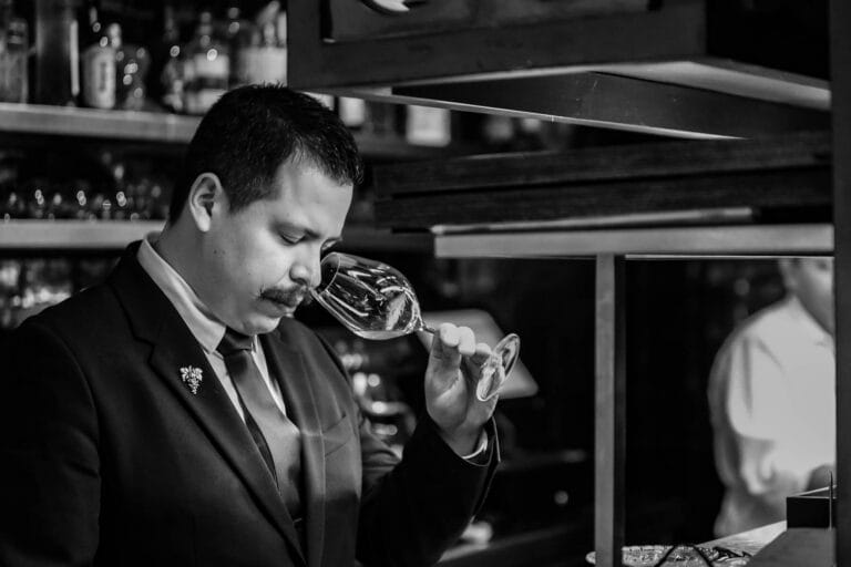 Camarero realizando una cata de vino en el restaurante Disfrutar de Barcelona, fotografía en blanco y negro que transmite profesionalidad y elegancia.