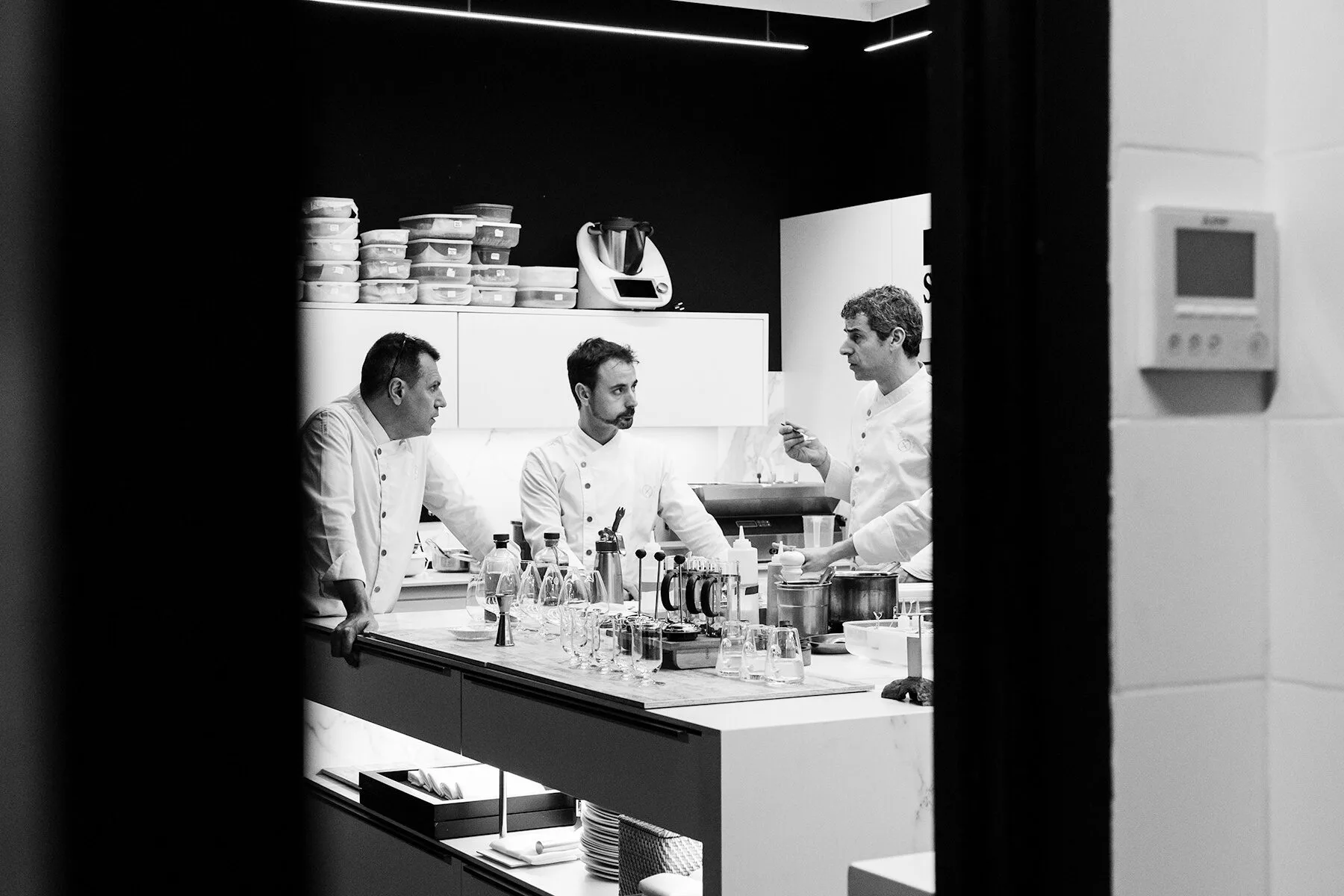 Chefs reunidos en la cocina del restaurante Disfrutar en Barcelona, fotografía en blanco y negro que refleja concentración y trabajo culinario.