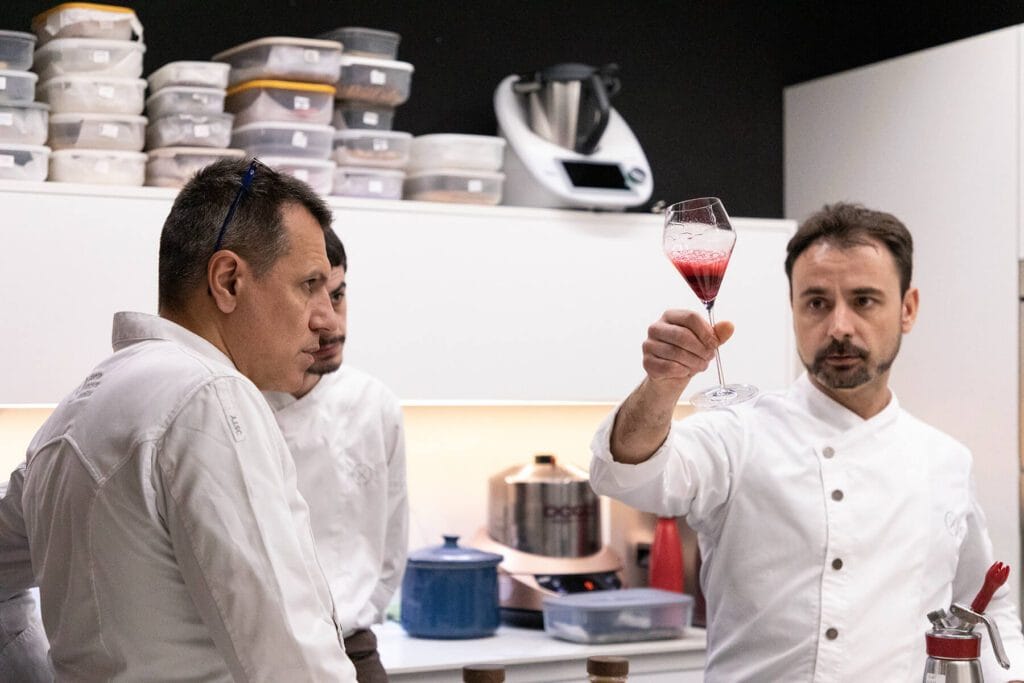 Tres chefs observan con atención la reacción de un vino espumoso en la cocina del restaurante Disfrutar en Barcelona.