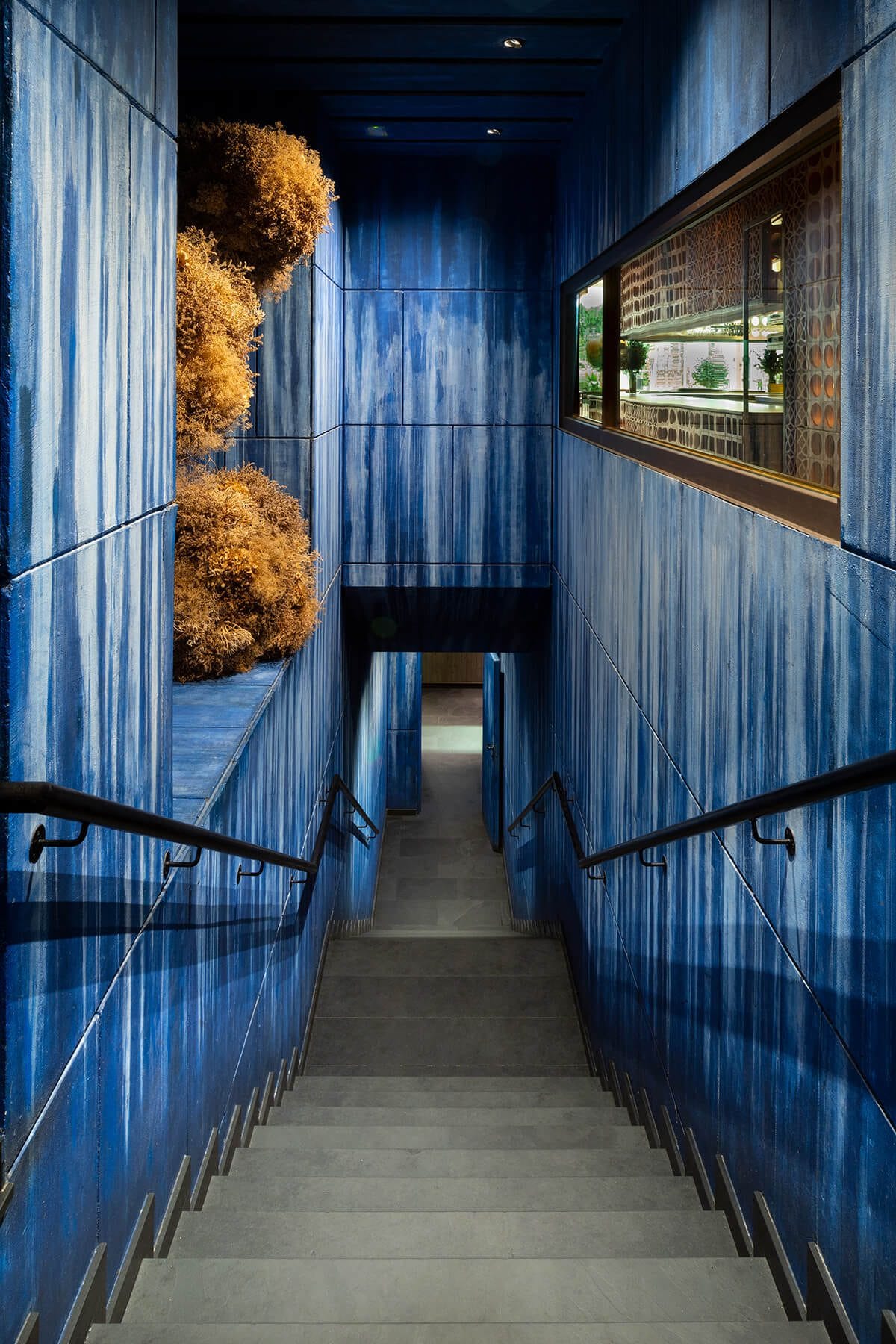 Escaleras interiores del restaurante Disfrutar en Barcelona vistas desde arriba, con paredes estampadas en azul y color llamativo.