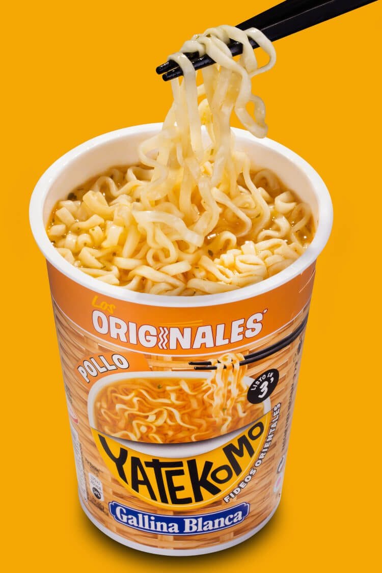 Fotografía profesional del Yatekomo de Gallina Blanca original de pollo abierto con palillos chinos sobre fondo naranja