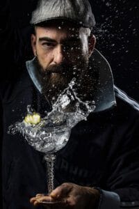 Retrato profesional de Rubén, bartender en acción batiendo un cóctel con salpicaduras sobre fondo negro, fotografía gastronómica, publicitaria y productos en Barcelona, España.