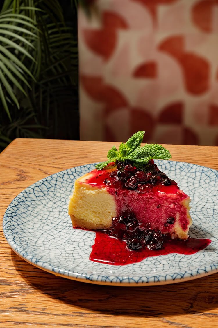 Cheesecake con salsa de frutos del bosque, postre gourmet fotografiado profesionalmente en Oasis Natural Cooking, Barcelona.