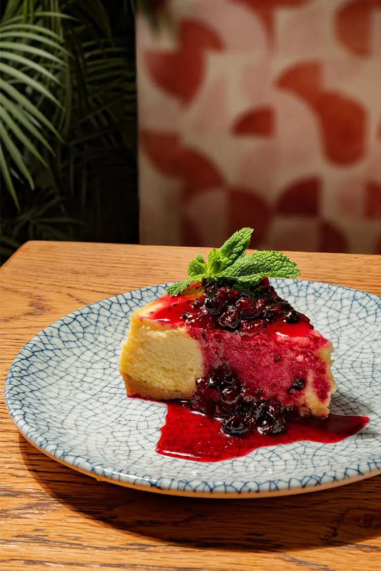 Cheesecake con salsa de frutos del bosque, postre gourmet fotografiado profesionalmente en Oasis Natural Cooking, Barcelona.