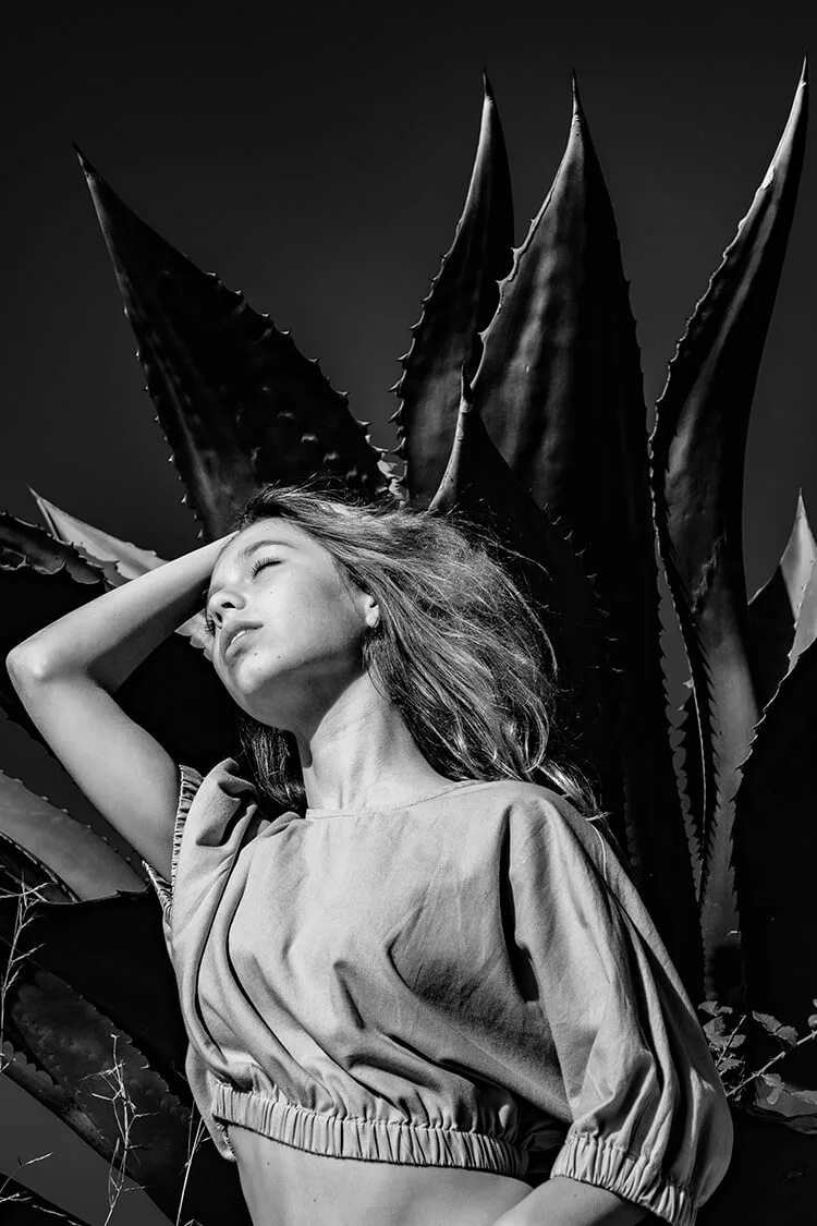 Retrato artístico en blanco y negro de una chica joven con fondo natural de aloe vera, realizado por fotógrafo profesional en Barcelona.