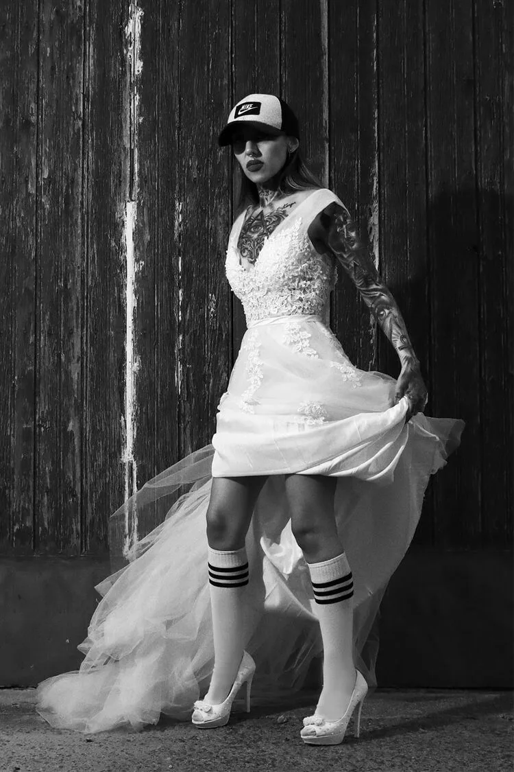 Retrato profesional en blanco y negro de una novia alternativa con vestido de boda, gorra Nike y calcetines deportivos, realizado por fotógrafo de retratos en Barcelona.