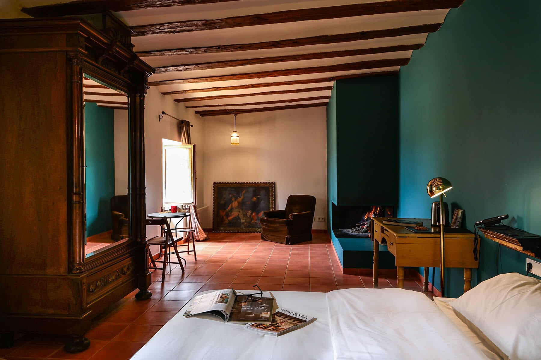 Habitación completa de hotel rústico en Teruel con cama grande, armario, sillón y vigas de madera