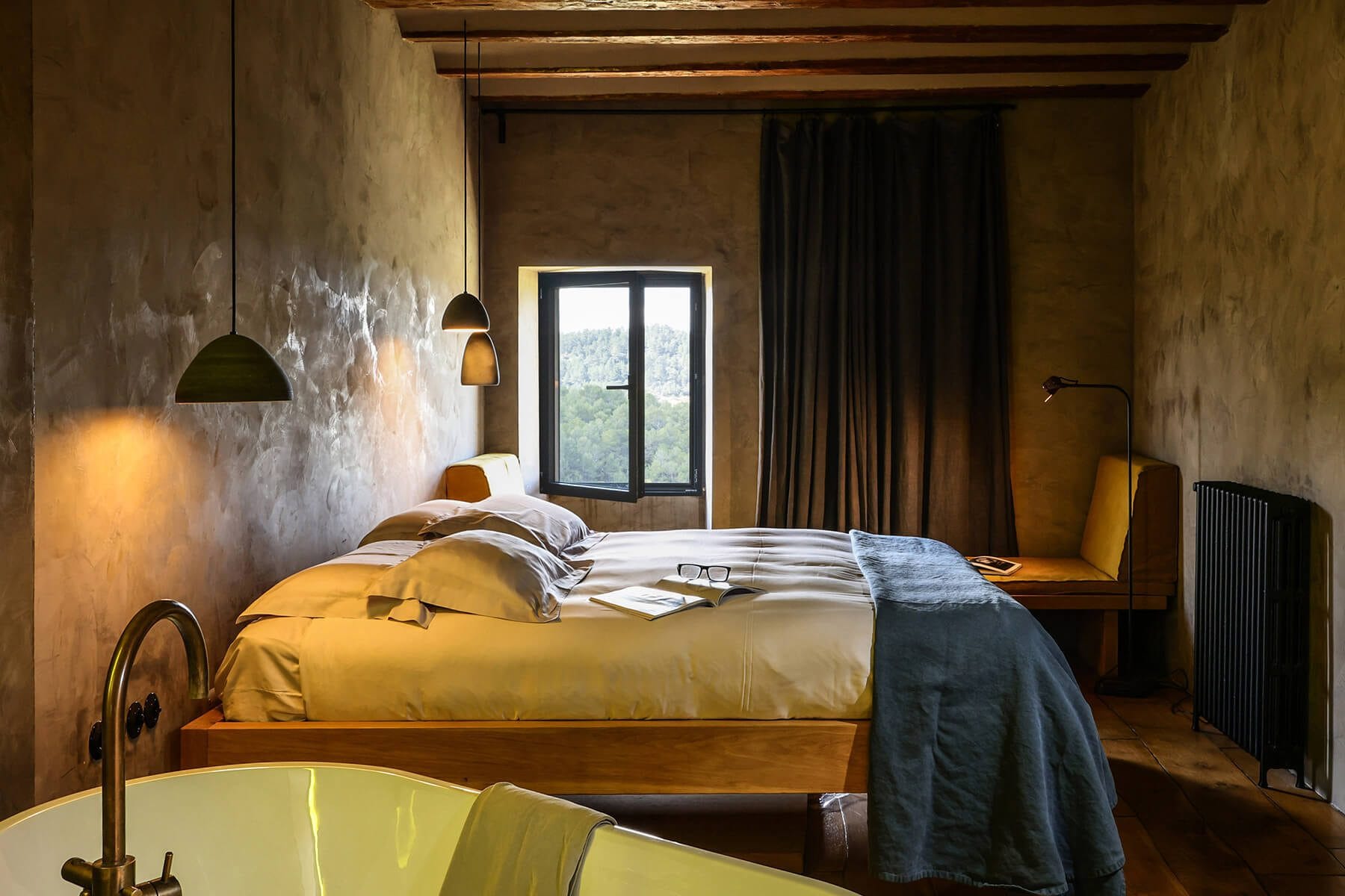 Habitación de hotel rústica y vintage en Teruel con cama grande y vigas de madera.