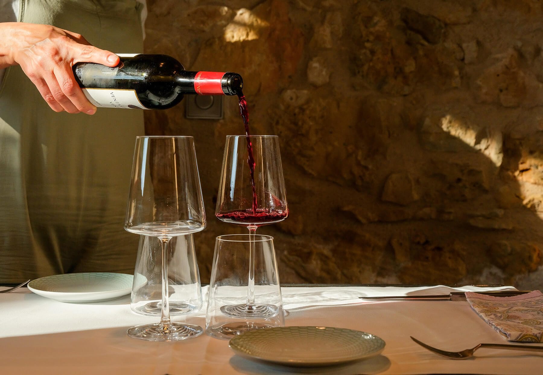 Mesa con platos y copas de vino, camarero sirviendo en restaurante de Teruel