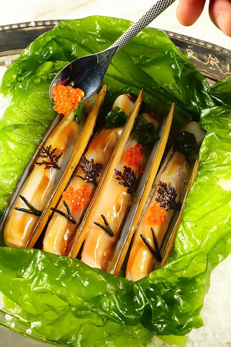 Navajas de Porto Muiños presentadas sobre lechuga con caviar rojo de salmón y trozos de alga en restaurante Compartir Barcelona, fotógrafo profesional.