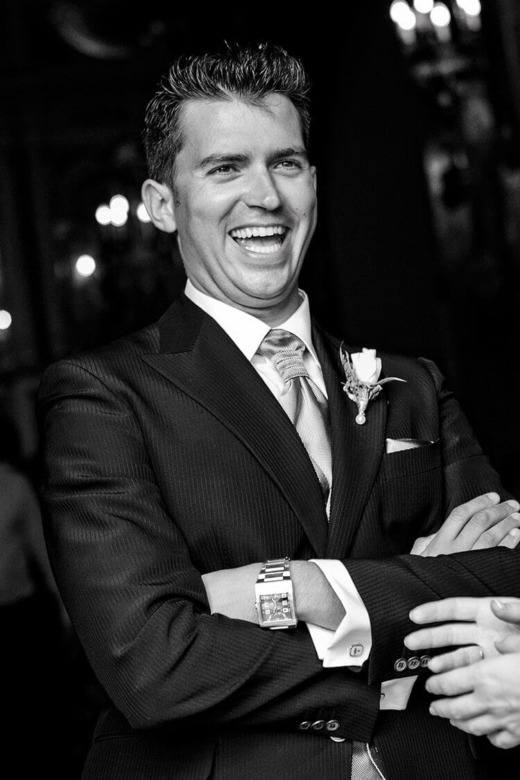 Retrato en blanco y negro del novio riendo elegantemente en boda en Barcelona