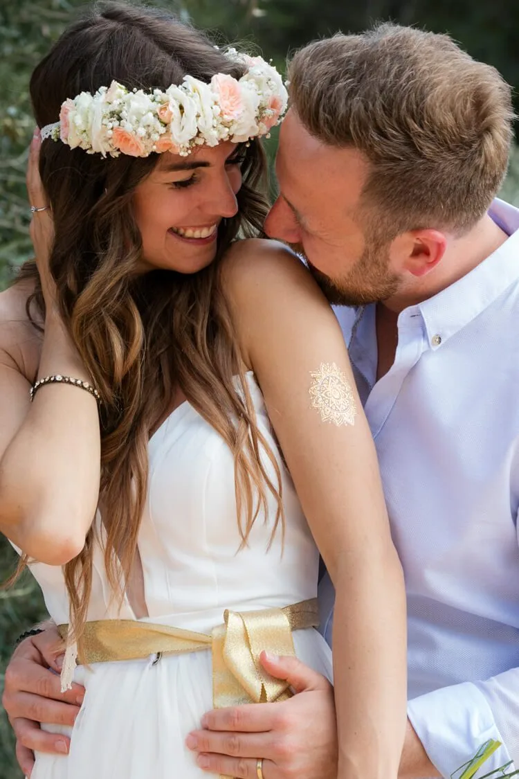 Retrato de pareja abrazada riendo en boda en las costas de Barcelona, novia con ramillete en la cabeza. Fotógrafo profesional en España.