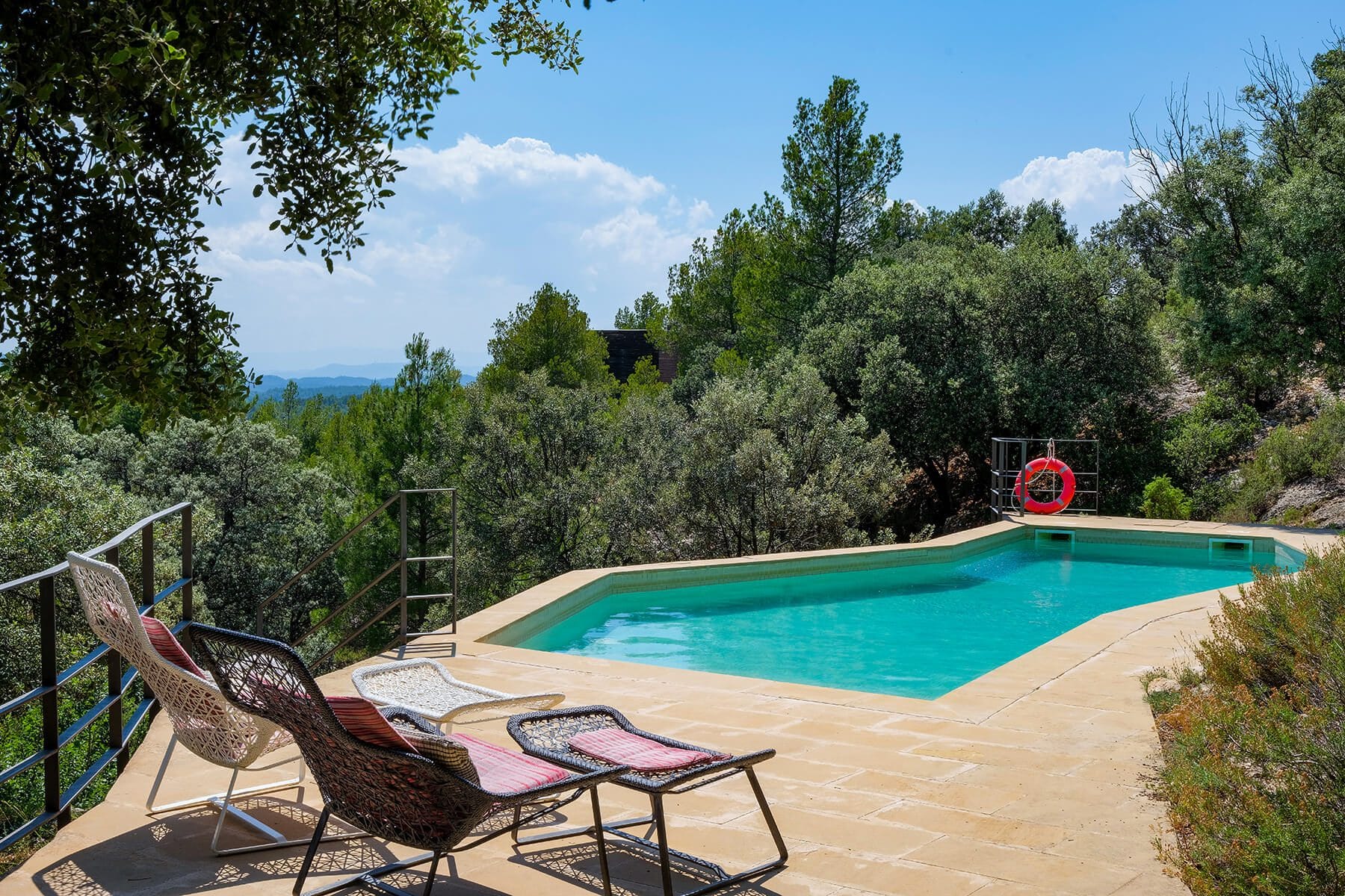 Piscina tranquila en la montaña rodeada de hamacas y árboles en Teruel