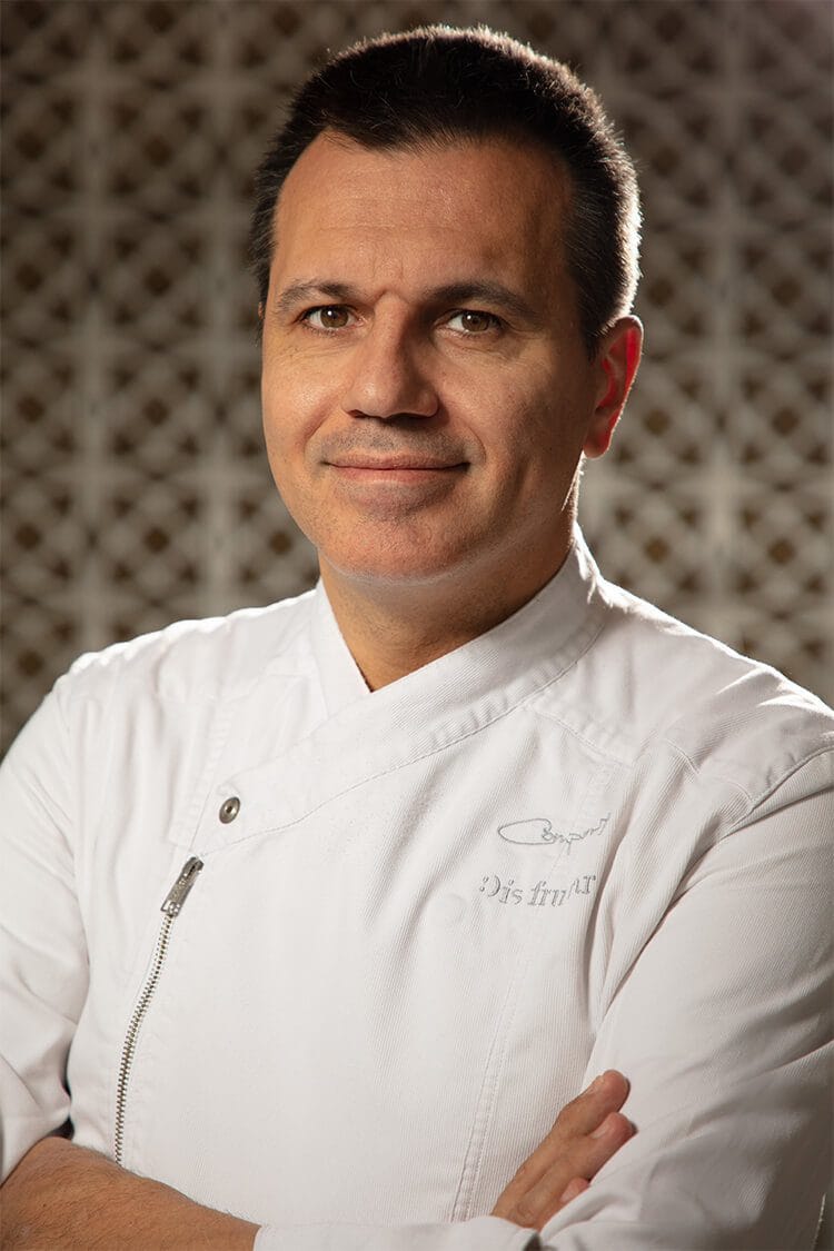 Retrato profesional de Oriol, chef en el restaurante Disfrutar de Barcelona, mostrando su rostro de perfil con expresión concentrada y experta.