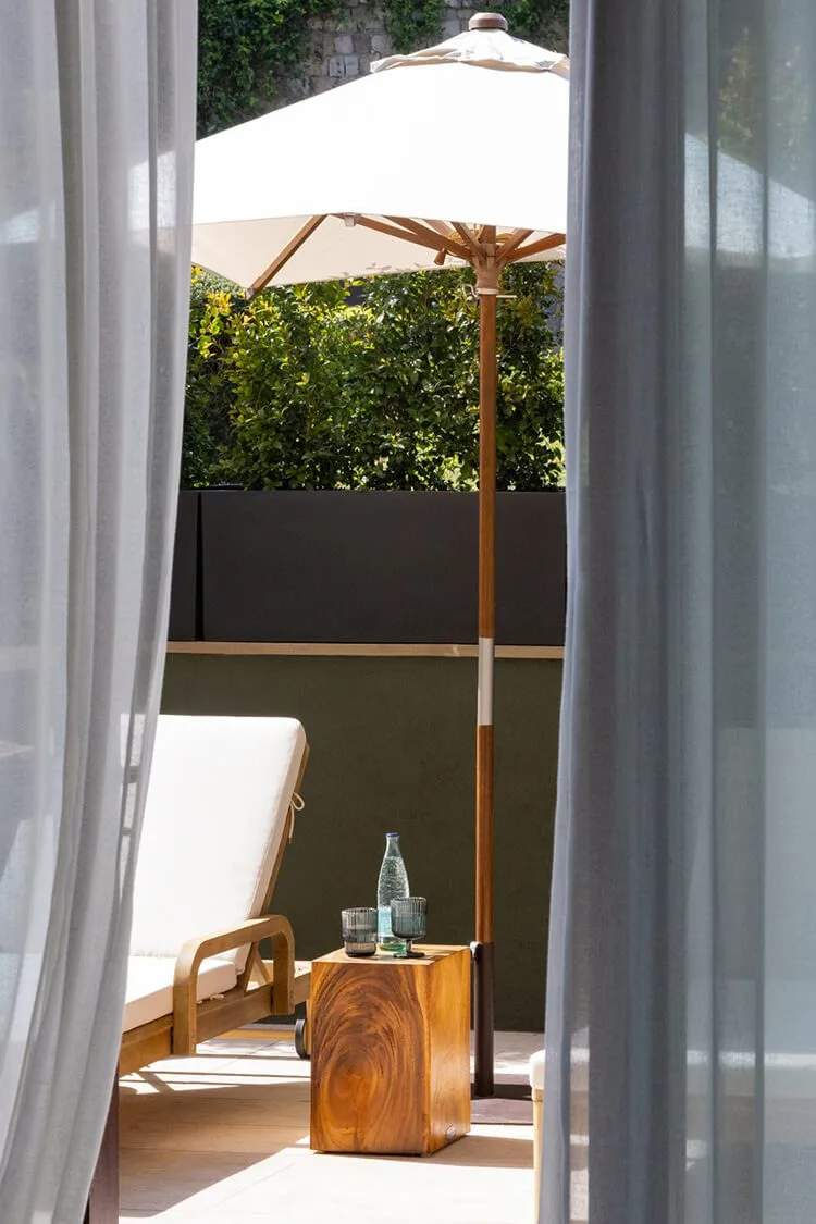 Fotografía profesional de la terraza de una habitación del Hotel Miramar en Barcelona con sombrilla blanca, hamaca y bebidas bajo el sol