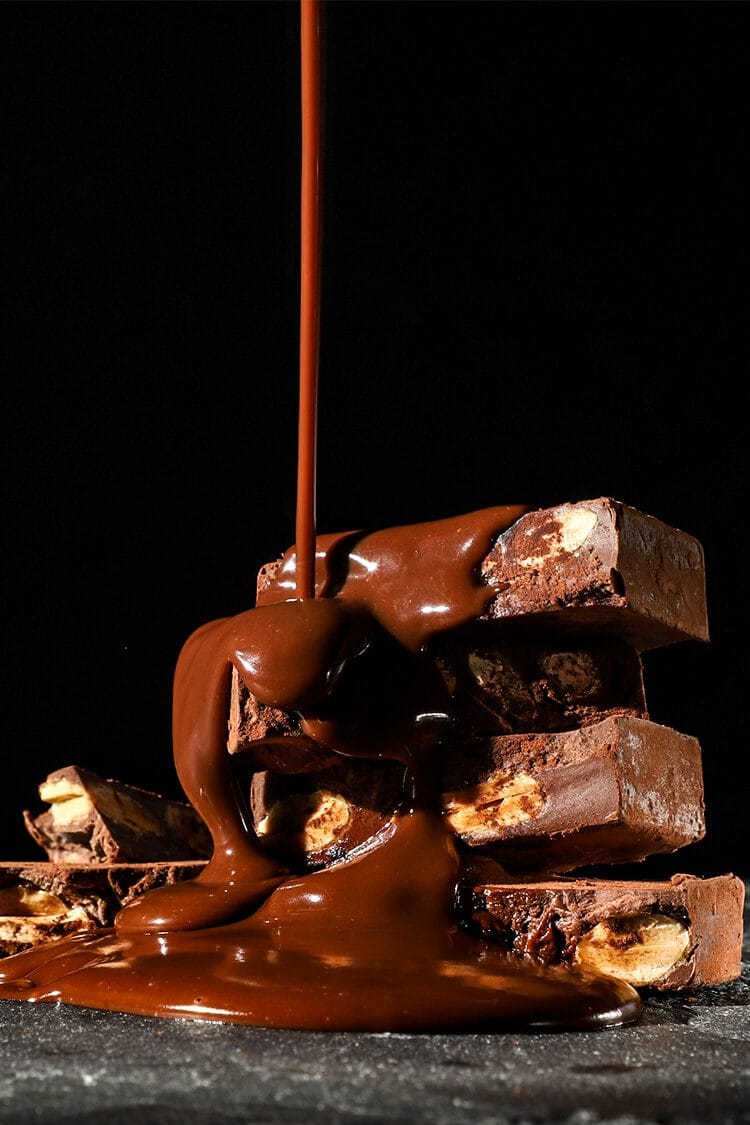 Turrones gourmet Catanias Cudié apilados con chocolate derretido, producto en fondo negro. Fotógrafo profesional de publicidad y productos en España.