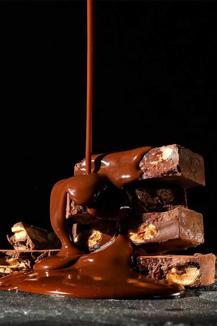 Turrones gourmet Catanias Cudié apilados con chocolate derretido, producto en fondo negro. Fotógrafo profesional de publicidad y productos en España.