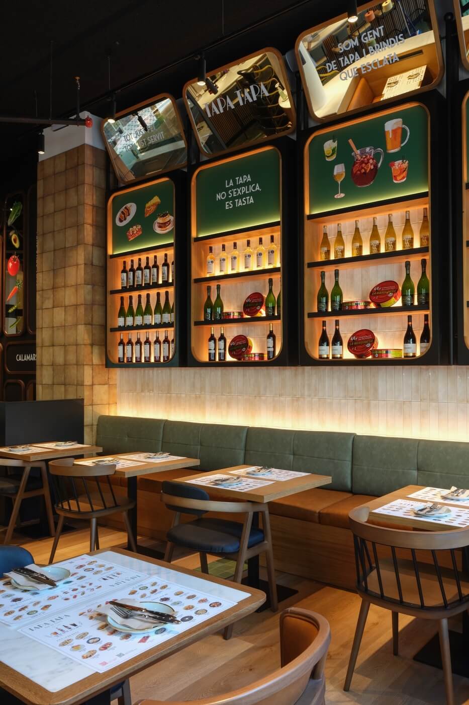 Vista vertical de estanterías con vino y mesas servidas en restaurante Tapa Tapa.