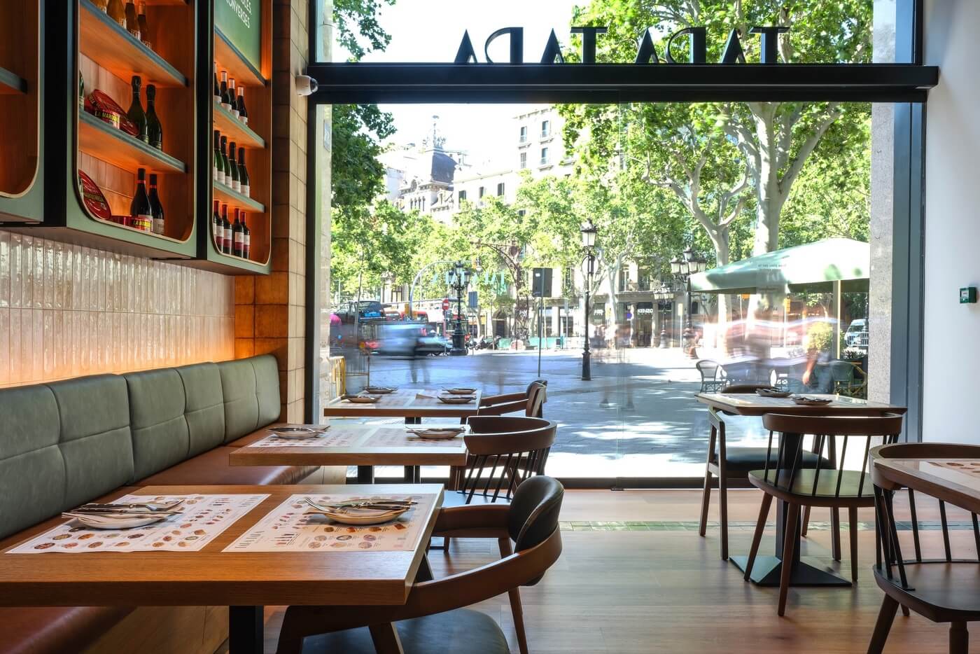 Interior del restaurante Tapa Tapa en Barcelona con vista hacia la entrada y cristalera abierta a la calle.