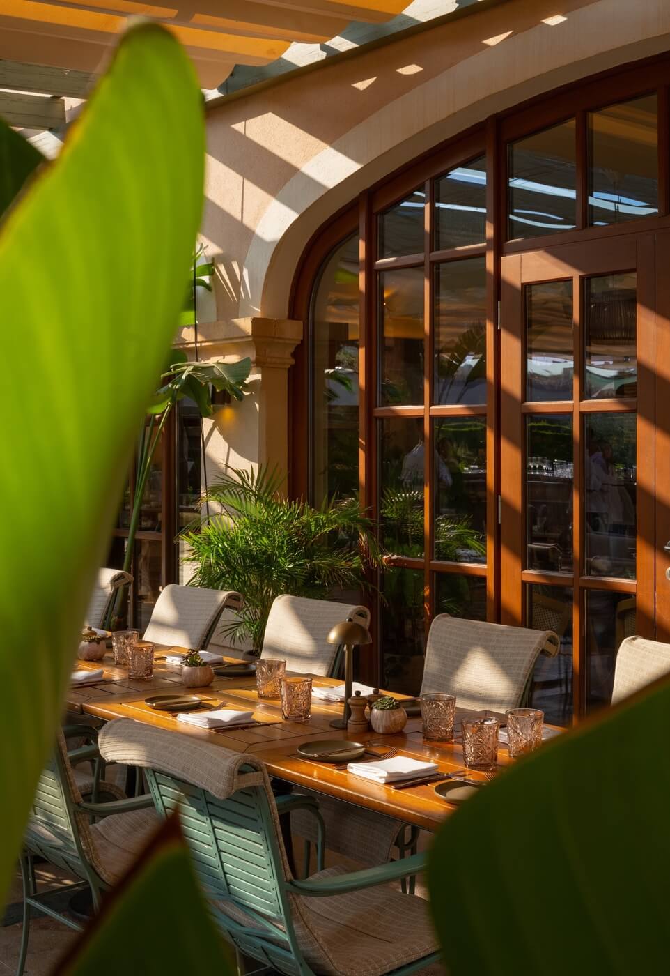 Fotografía profesional de mesa de restaurante con hojas de palmera en primer plano en hotel St. Regis Mardavall Mallorca