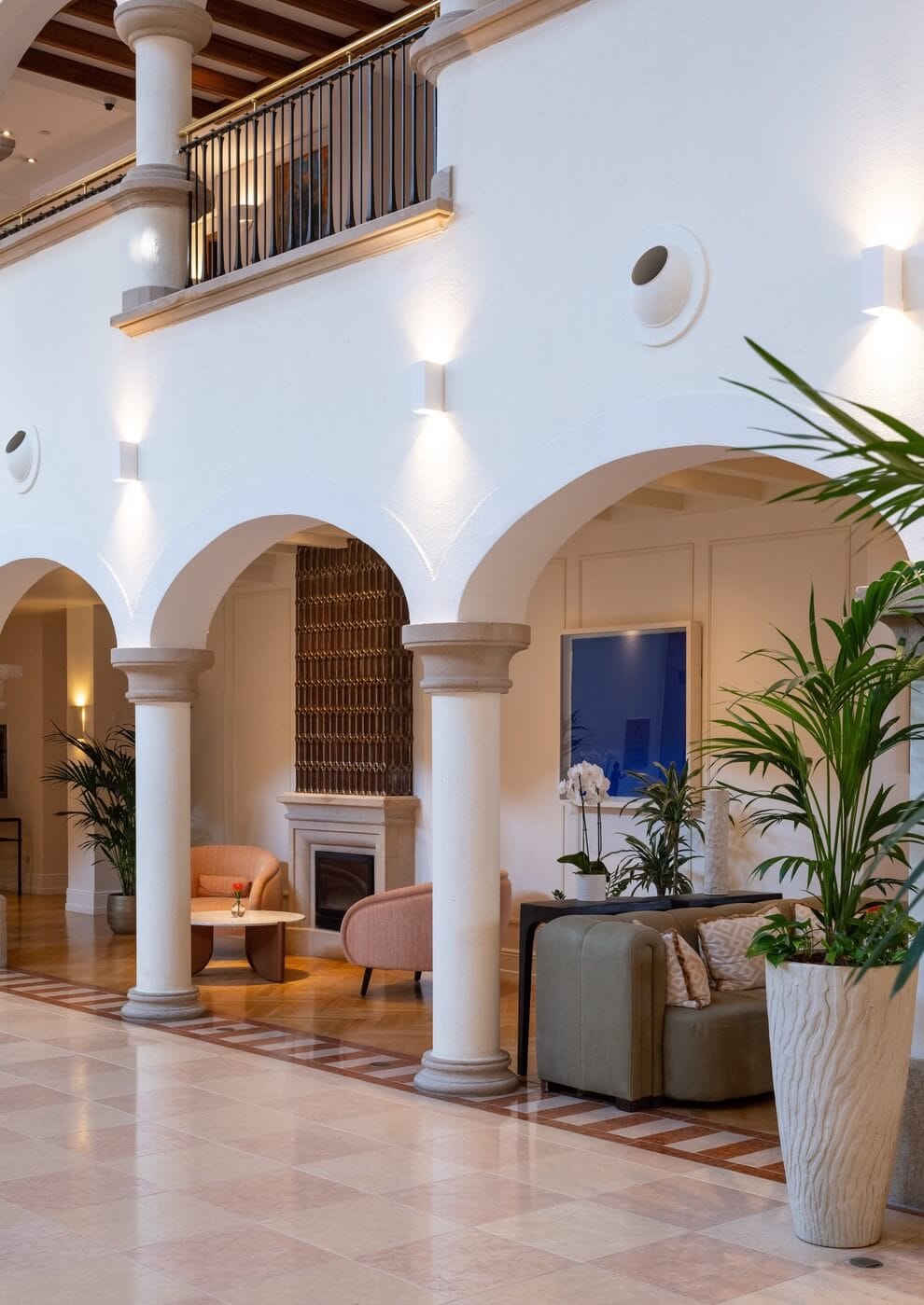 Fotografía profesional de interior de hotel con patio, columnas griegas, fachada blanca y salón acogedor con chimenea en Mallorca.