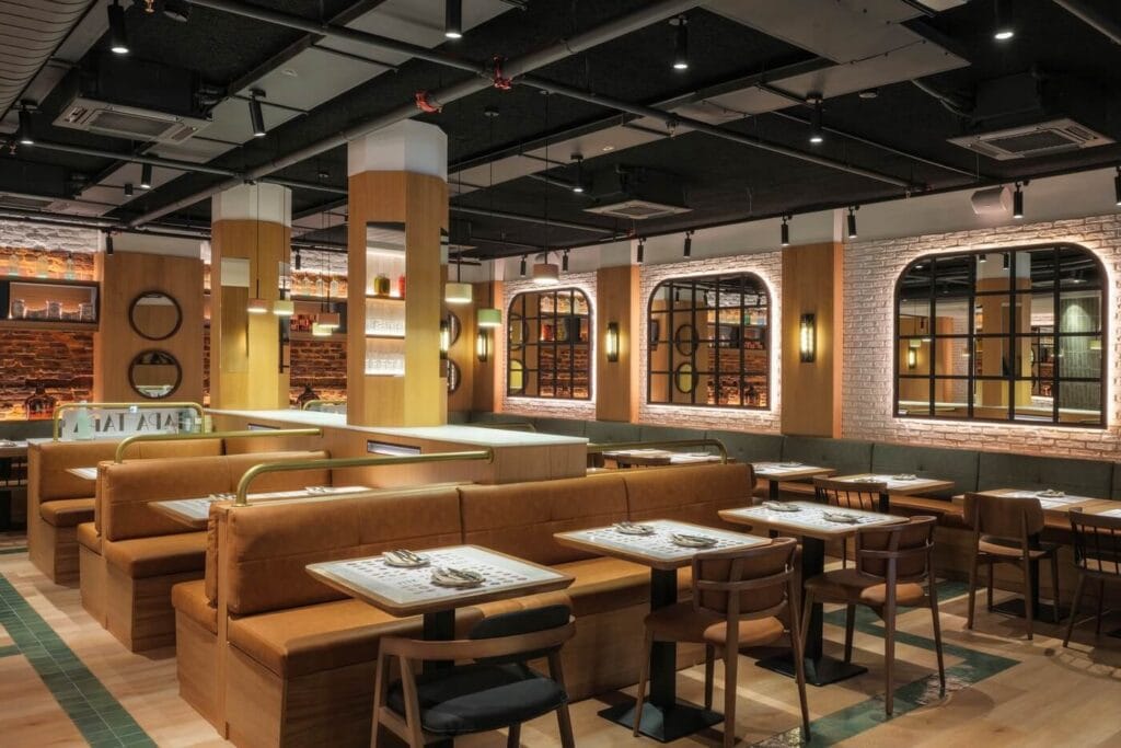 Fotógrafo profesional del interior del restaurante Tapa Tapa en Barcelona, España, con mesas para dos, ladrillo visto y espejos decorativos.