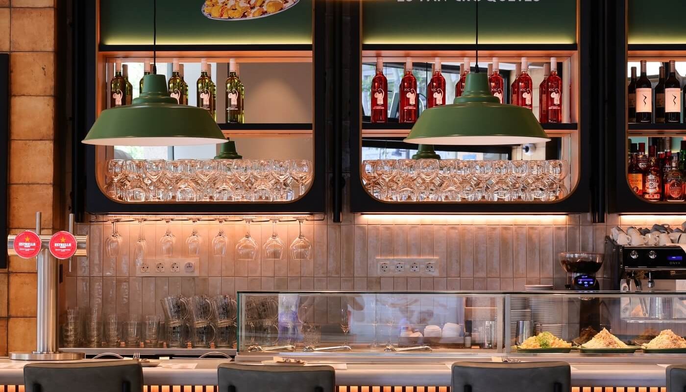 Primer plano de la barra del restaurante Tapa Tapa con vitrina de tapas, copas y vinos.