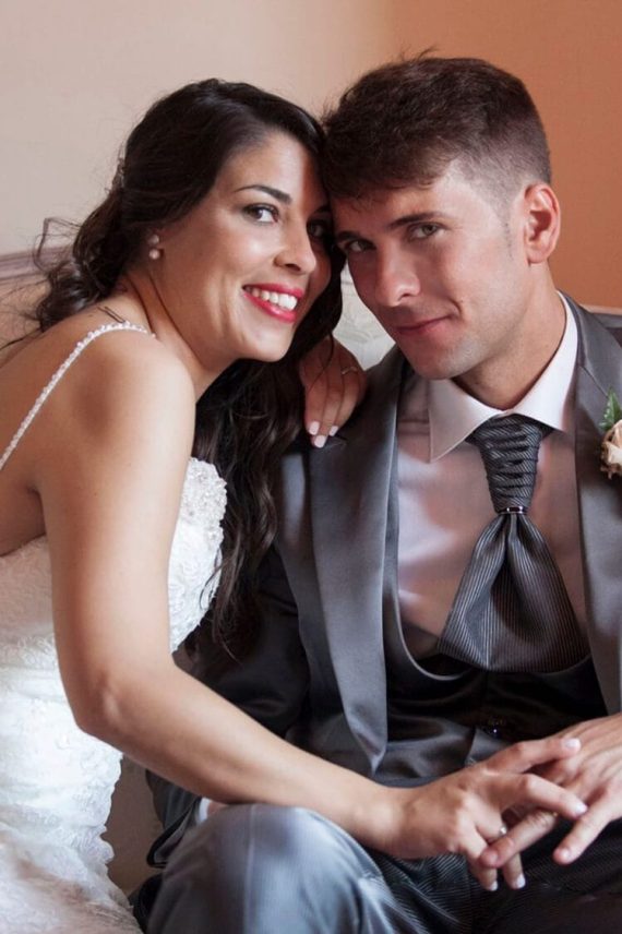 Retrato de pareja elegante sentada y sonriente en boda en Barcelona