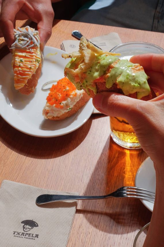 Fotografía gastronómica de clientes disfrutando tapas y ternera al punto en el restaurante Txapela de Madrid.